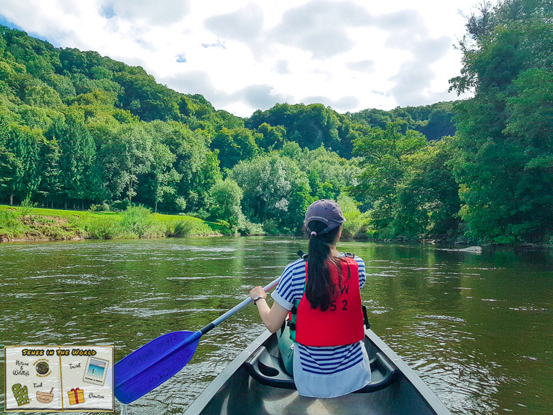 Me paddling a canoe along the River Wye in Wales in mid-July 2020, with a view of green woods. Image taken by Josh - Sehee in the World